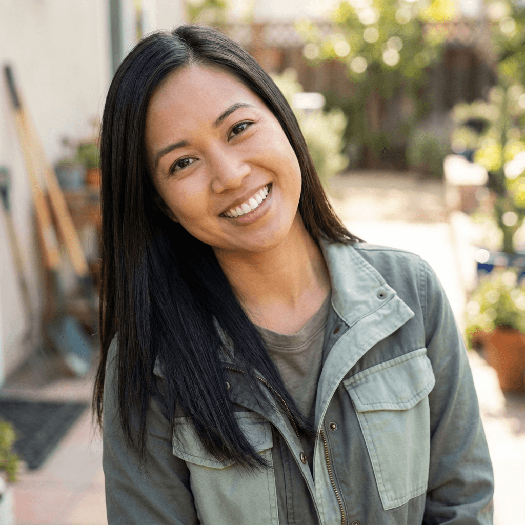 Female plant specialist smiling while adjusting a potted fern on a shelf